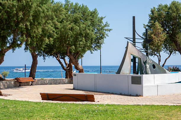 Protaras. Famagusta area. Cyprus. Umbrellas from the sun made of natural materials and sun loungers on the grass, among the trees on the shores of the Mediterranean Sea against the blue cloudless sky.