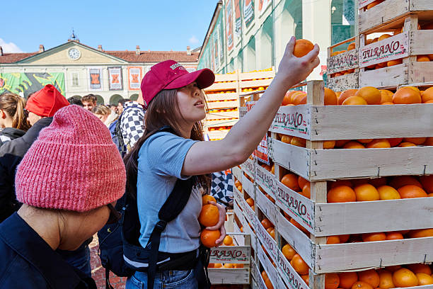 Ivrea, Italy - March 02, 2025: an Asian tourist picking up oranges before the arrival of the next cart at the \