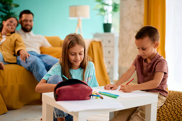 istock Happy children drawing with colorful pencils while parents relaxing on sofa 2227153541