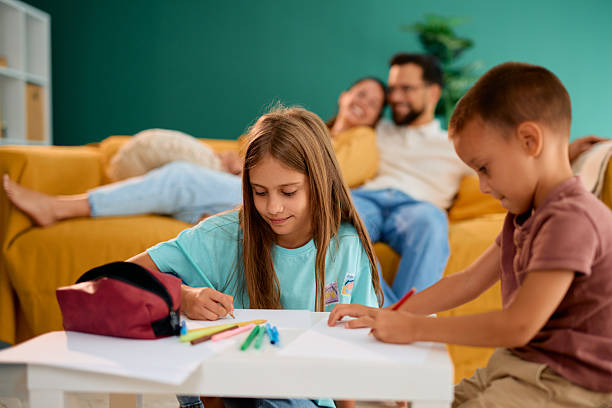 istock Happy children drawing with colored pencils while parents relaxing on sofa 2227153616