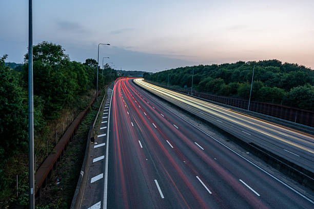 istock Light trails illuminating highway at dusk with trees on side 2227157122