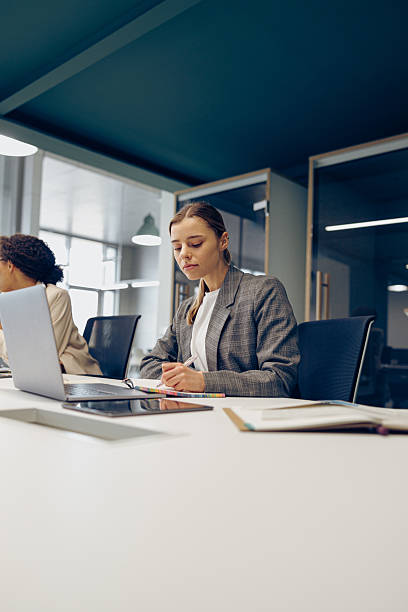istock Focused female freelancer working on laptop while sitting in modern coworking. Distance work concept 2227159381