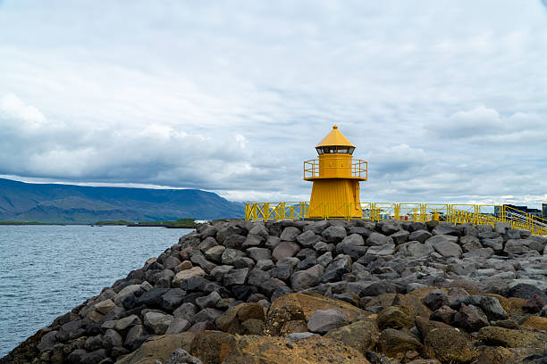 A yellow light house on the edge of the sea in Reykjavik Iceland