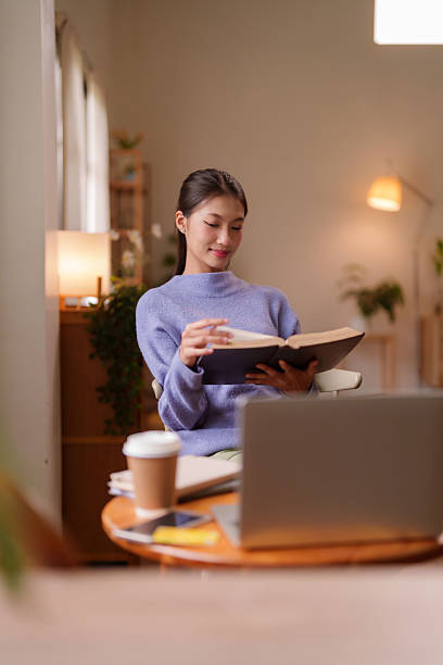 istock Young Asian woman reads book home cozy environment student learns new knowledge freelancer relaxation digital nomad leisure time comfort lifestyle 2227180858
