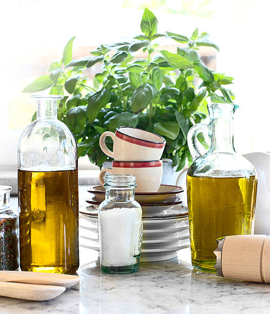A bowl of pasta is sitting on a counter next to two bottles of oil. The bowl is filled with pasta and vegetables, and the bottles are filled with oil. The scene is set in a restaurant or a kitchen