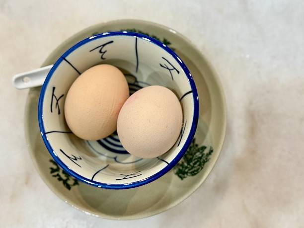 istock Two soft boiled eggs in porcelain bowl and spoon with copy space 2227186441