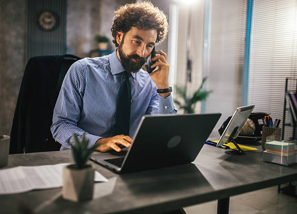 istock smiling businessman having a phone call while working on laptop in modern office 2227191251