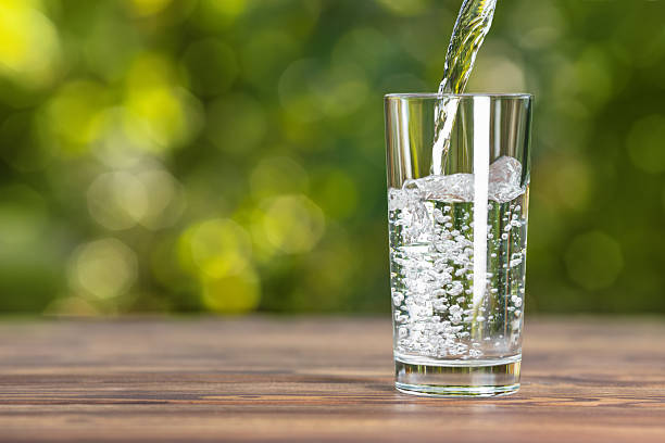 istock Drink water pouring into glass on wooden table 2227194401