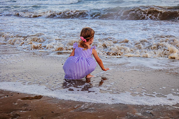 Evening time, girl on the seashore, enjoying huge waves, in cloudy weather