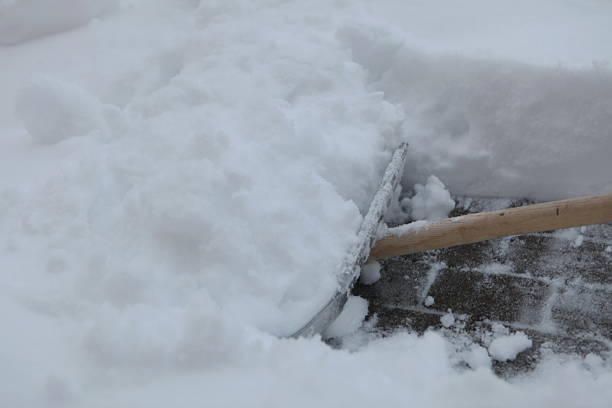 Snow shovel is being used to clear snow from a sidewalk. The snow is piled up high, and the shovel is being used to push it aside. Concept of hard work and determination