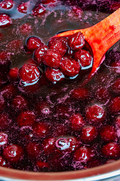 istock Preparing freshly picked red cherries with sugar to make cherry jam in a saucepan with a wooden spoon, closeup. Cooking berries marmalade, home cooking 2227201483