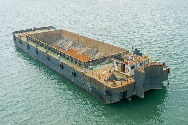 istock Rusty barge loaded with dredging sediment floating in calm tropical waters 2227204433