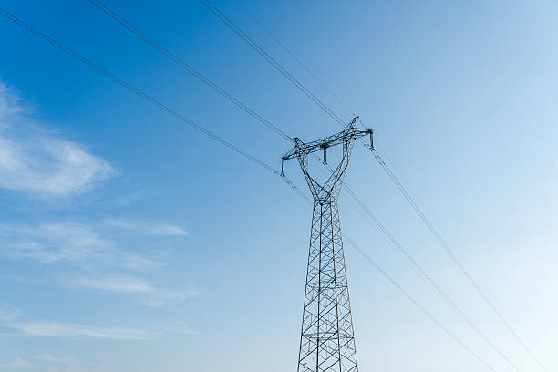 high voltage transmission tower under clear blue sky - torre de alta tensão imagens e fotografias de stock