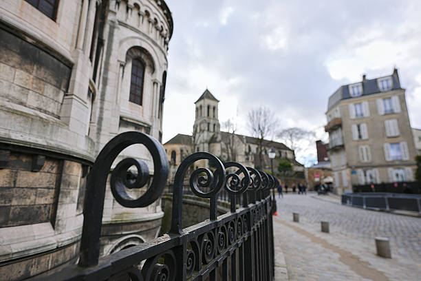 View of Paris street and Sacre Coeur wall through black wrought iron railing
