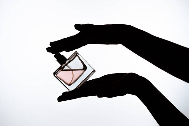 istock Elegant Glass Perfume Bottle Held by Silhouetted Hands 2227212955