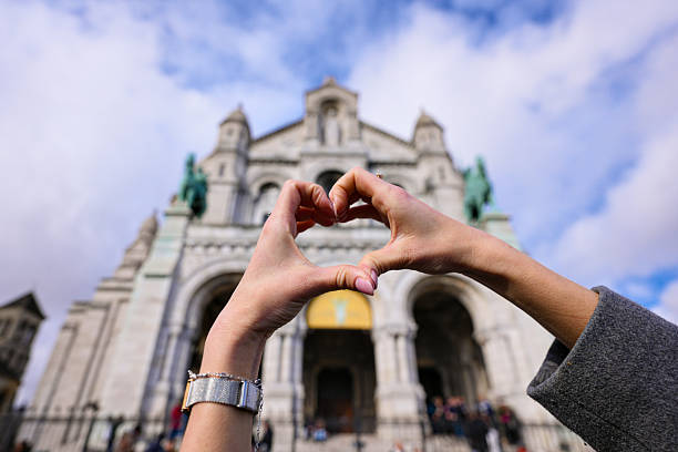 Tourist hands creating heart gesture in front of Sacre Coeur cathedral in Paris France