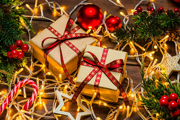 istock Two brown gift boxes near Christmas tree. Sparkling string lights and ornaments. Tradition or present and surprise for bonding, season for giving, festive and decoration for event 2227214196