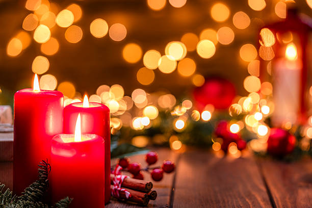 istock Three burning Christmas decore candles on rustic wooden table. Christmas backgrounds, warm tones or gold colors. Cozy December atmosphere, spirituality and tradition 2227214242