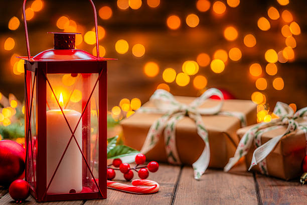 istock Cozy Christmas decoration with burning lantern, gift boxes and spotted string lights at background. Spirituality and December tradition. Gold colors and warm tones 2227214245