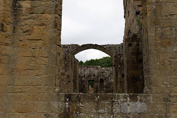 istock A stone archway is viewed through a crumbling stone wall in an old ruin. 2227215387