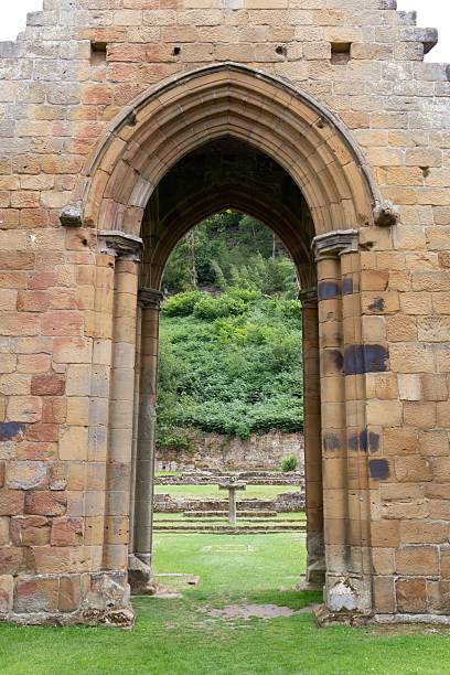 istock A stone archway frames a view of a grassy area and trees. 2227216188
