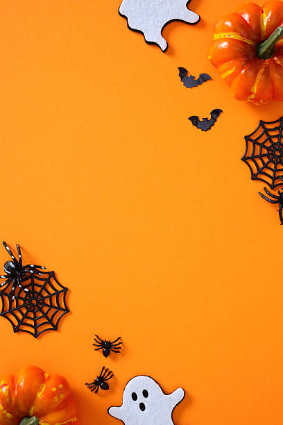 istock Halloween flat lay with pumpkins, ghosts, bats, spider webs and spiders on vibrant orange backdrop 2227218190