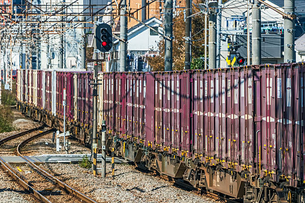 Japanese Rail Freight Containers Passing through Dense Suburbia in Kawasaki-Kanagawa Prefecture in Tokyo en route to the port.  Non-polluting, electric freight railway with multiple similar rolling stock and standard freight containers.  Logos & ID edited.