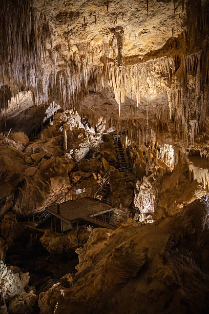 Illuminated Cavern Interior with Stalactites and Metal Walkways
