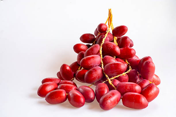 Fresh ripe red dates (Phoenix dactylifera) on a white background. Vibrant and exotic tropical fruit perfect for health, food, nutrition, or natural product concepts.
