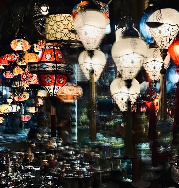 A mesmerizing long-exposure photograph capturing a vibrant array of traditional Turkish lamps in a market in bazaar, Gaziantep, Turkey. The handcrafted mosaic and glass lanterns create a dreamy motion blur effect, showcasing the dynamic energy, color, and cultural richness of the bazaar. Ideal for themes of Turkish heritage, artisanal craftsmanship, cultural tourism, and exotic market scenes.