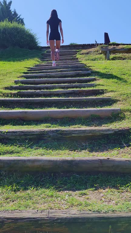 Determined sportswoman climbing wooden stairs in a park, demonstrating fitness and dedication to exercise