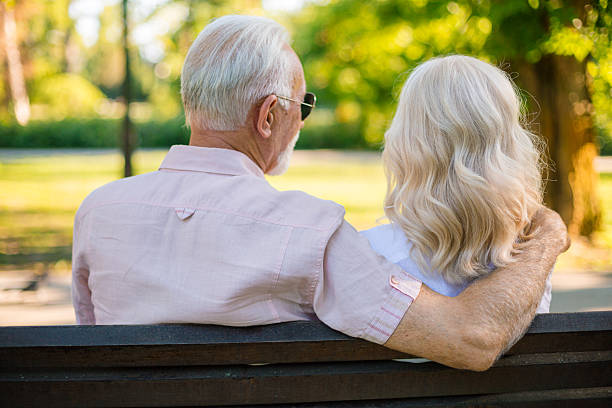istock Senior couple relaxing on park bench together 2227230676