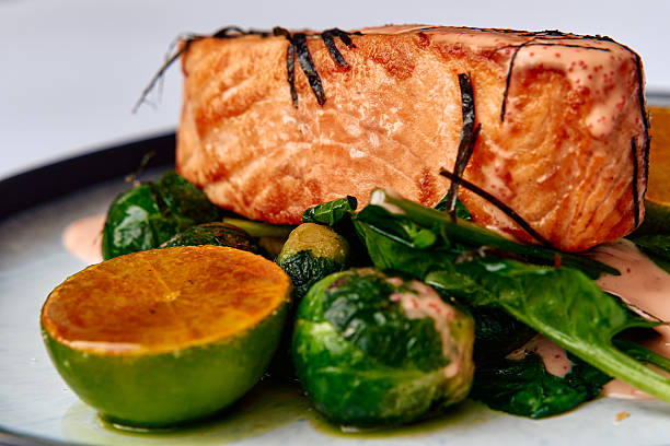 A beautifully plated dish featuring expertly grilled salmon fillet served with a medley of fresh vegetables and zesty lime, perfect for healthy dining.