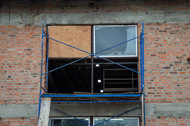 istock Renovation activity occurring on a brick building, showcasing an open window framed with scaffolding and temporary wooden covering 2227233611