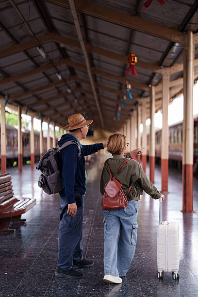 istock Older Asian Couple Explore Travel Train Station Platform Pointing Direction Begin Exciting Journey Retirement Vacation Lifestyle Adventure Trip 2227233995