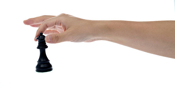 Human hand holding chess queen on white background.