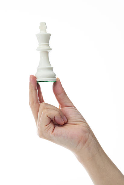 Human hand holding chess king on white background.