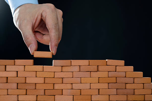 istock Businessman putting toy brick onto a wall 2227235835