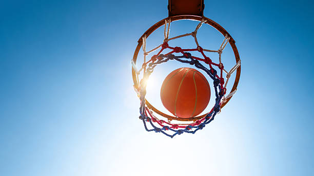 Basketball in a net against blue sky