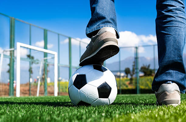 Man standing with his feet on ball in stadium