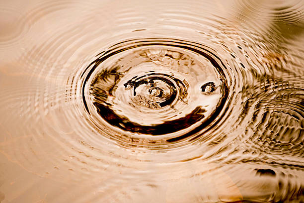 istock Raindrops falling on smooth surface of water. water droplets affect the surface. 2227236739