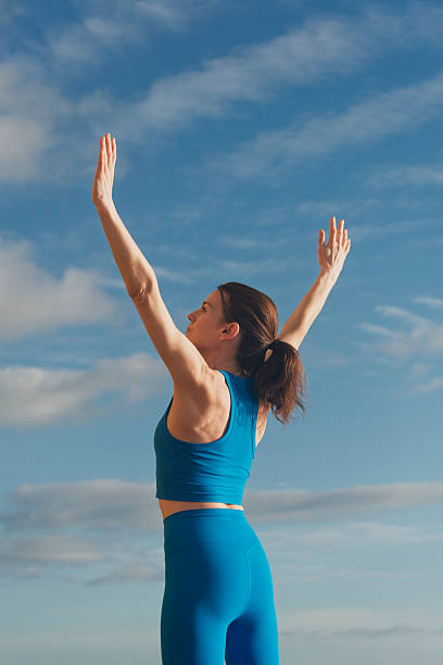 istock fit sporty woman doing stretching exercise with arms raised outdoors with a blue sky 2227237662
