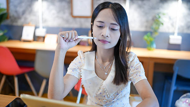 istock Young woman is thoughtfully engaged her work, using tablet while seated stylish desk modern workspace. environment features blend of contemporary furniture and decorative elements, creating 2227237825