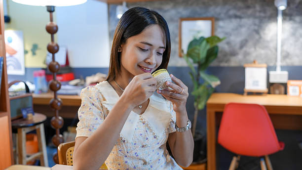 Young woman enjoys cupcake in cozy cafe setting, showcasing moment of delight and indulgence. warm ambiance and stylish decor enhance experience