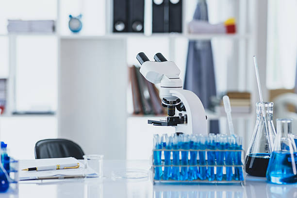 istock Laboratory glassware containing blue liquids is standing on table with microscope in modern laboratory ready for scientific experiment. 2227239026