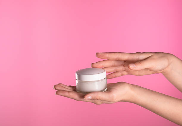 istock Hand Holding White Cream Jar on Pink Background 2227239521