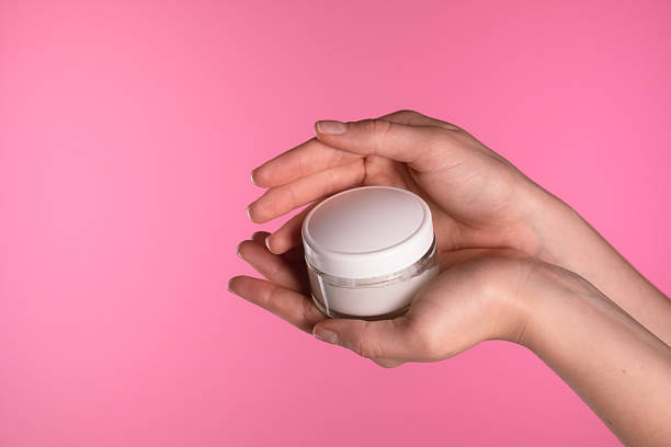 istock Hand Holding White Cream Jar on Pink Background 2227239788