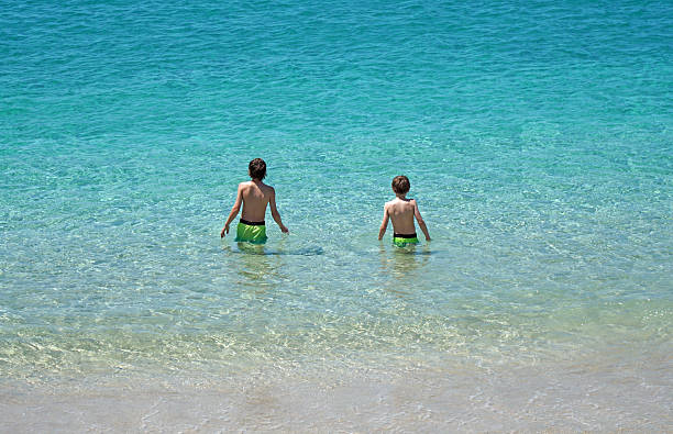 Playa Blanca, Lanzarote, Spain -  April 24, 2024:  Two boys standing in the blue sea