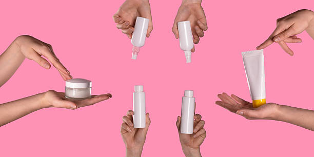 istock Variety of Hands Holding Different Cosmetic Containers on Pink Background 2227243210