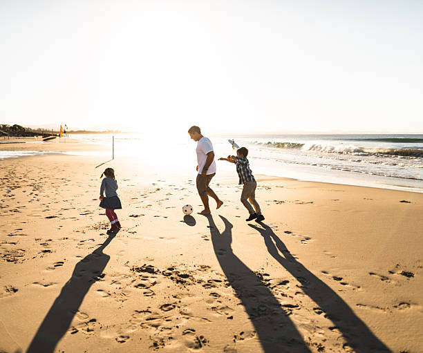istock dad and son playing soccer on the beach 2227245075